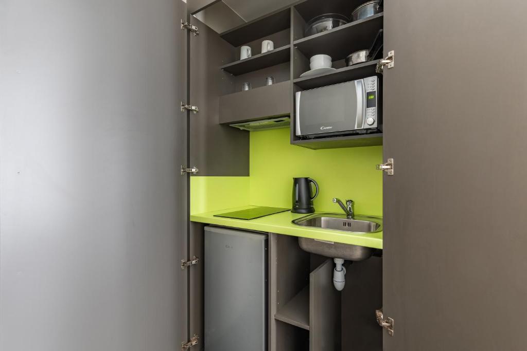 a small kitchen with a sink and a microwave at Appart’City Confort Le Bourget - Aéroport in Le Bourget