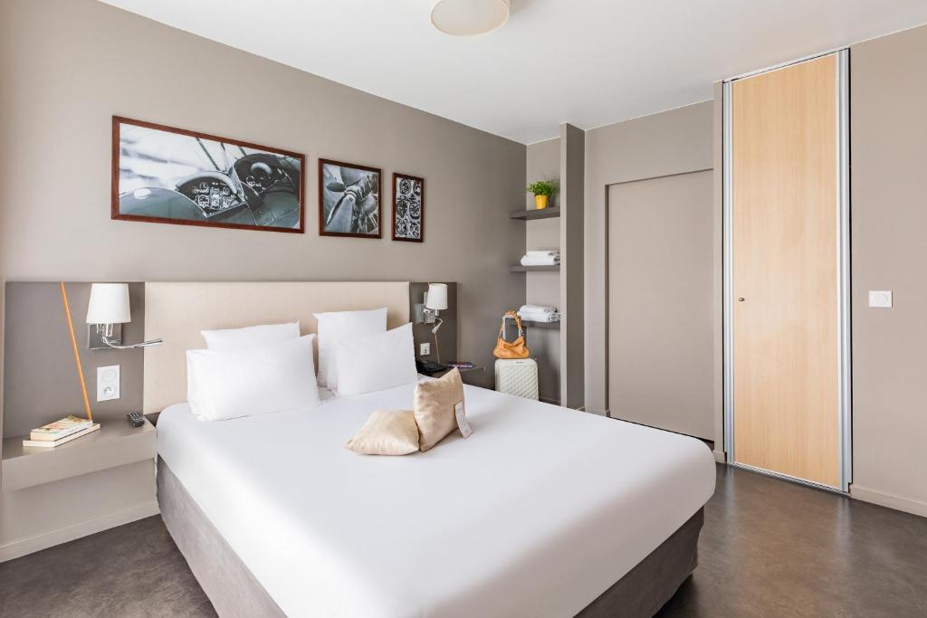 a bedroom with a large white bed in a room at Appart’City Confort Le Bourget - Aéroport in Le Bourget