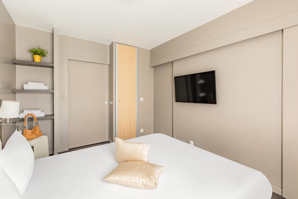 a bedroom with a bed and a tv on a wall at Appart’City Confort Le Bourget - Aéroport in Le Bourget