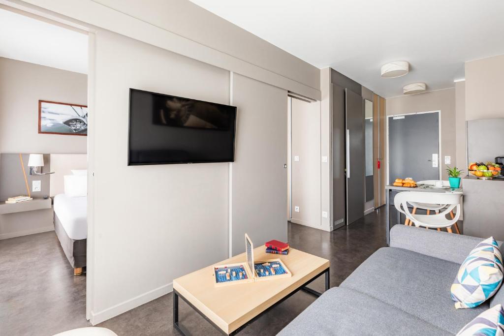 a living room with a couch and a table at Appart’City Confort Le Bourget - Aéroport in Le Bourget