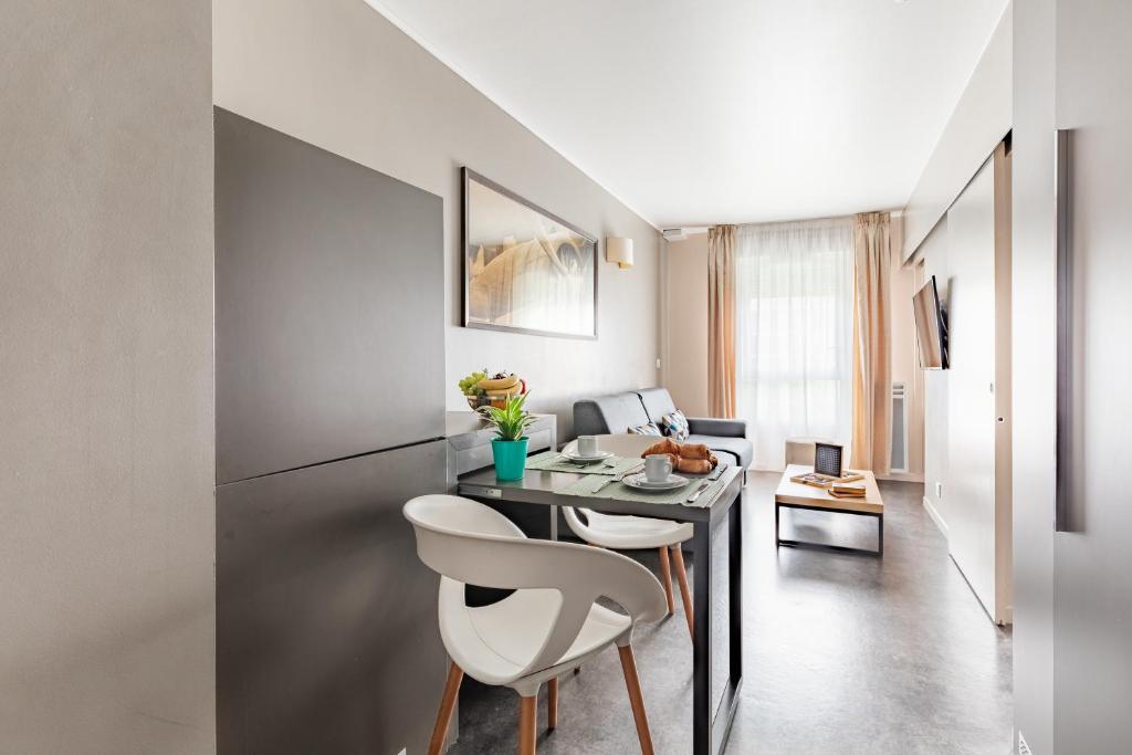 a kitchen with a table and two white chairs at Appart’City Confort Le Bourget - Aéroport in Le Bourget
