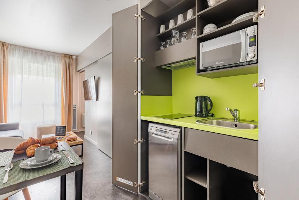 a small kitchen with a sink and a table at Appart’City Confort Le Bourget - Aéroport in Le Bourget