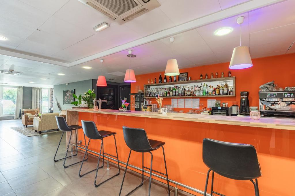 a bar in a restaurant with black stools at Appart’City Confort Le Bourget - Aéroport in Le Bourget