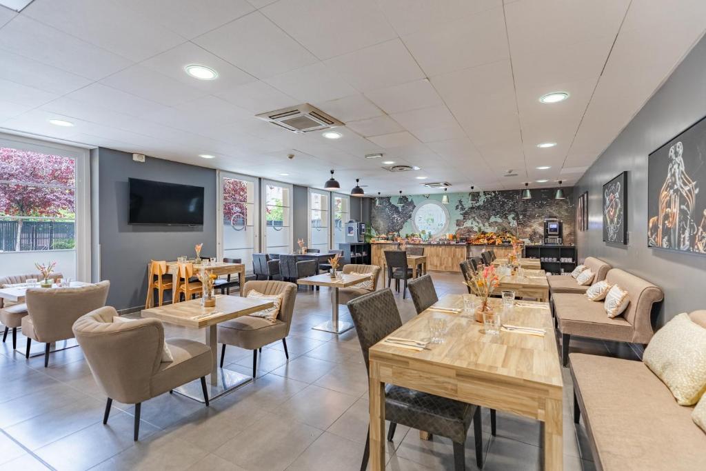 a restaurant with tables and chairs and a tv at Appart’City Confort Le Bourget - Aéroport in Le Bourget