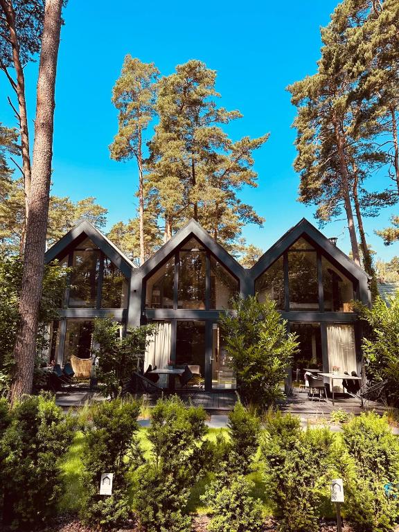 an exterior view of a house with trees at Forest House Pobierowo in Pobierowo