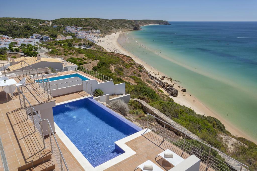 an aerial view of a house with a swimming pool and the beach at Villa Mar à Vista by VILA VITA Collection in Salema
