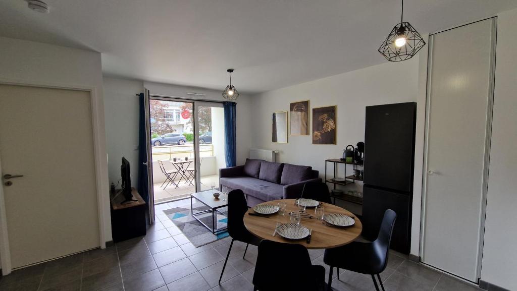un salon avec une table et un canapé dans l'établissement T2 avec Terrasse en ville, proche mer et campagne, à Saint-Nazaire