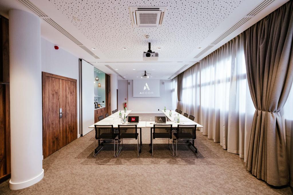 a conference room with a table and chairs and a curtain at Ibis Luxembourg Airport in Luxembourg