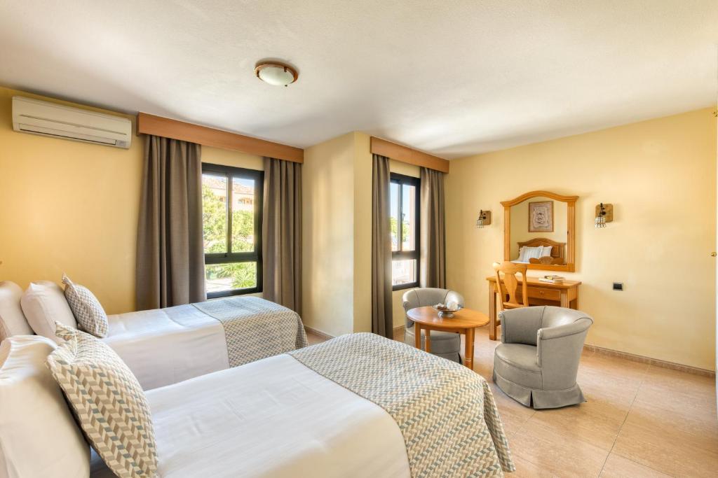 a hotel room with two beds and a desk at Macdonald Doña Lola Resort in La Cala de Mijas
