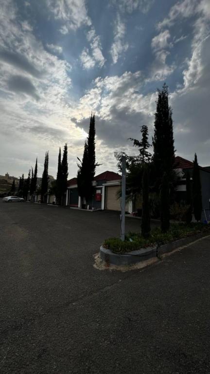 a parking lot with trees and a cloudy sky at منتجع وفلل المرفأ ابها in Abha