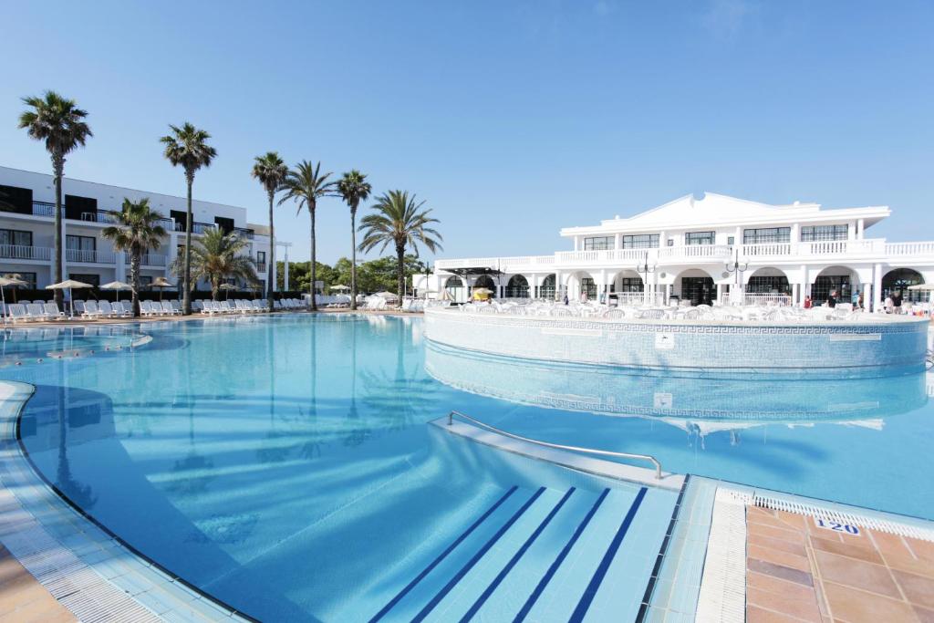 una gran piscina con un barco en el agua en Grupotel Mar de Menorca en Es Canutells