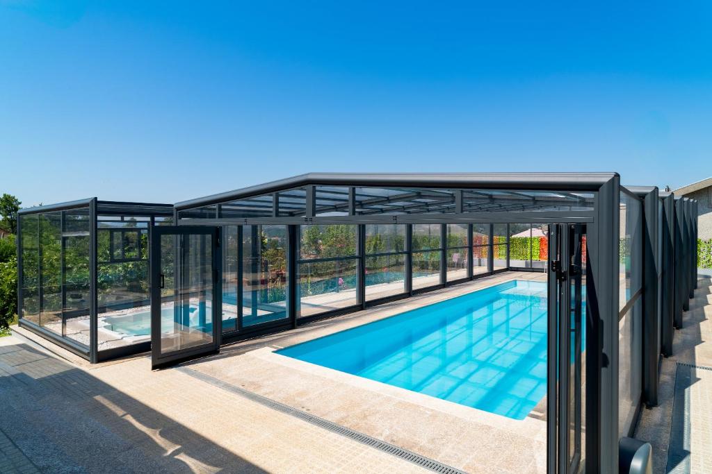 an aluminum pool house with glass walls and a swimming pool at Porto Vivenda em Lever-casa inteira in Lever