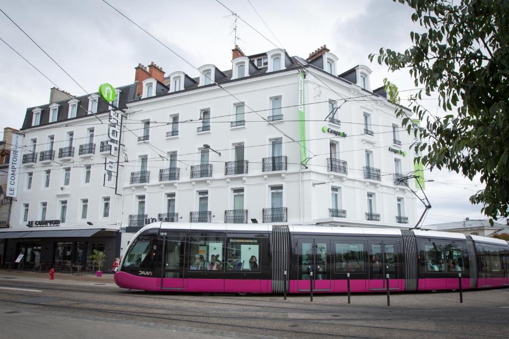 un tramway rose devant un bâtiment blanc dans l'établissement Campanile Dijon Centre - Gare, à Dijon
