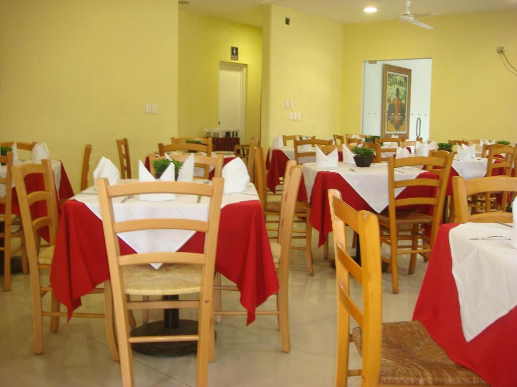 un comedor con mesas y sillas con servilletas rojas en Hotel Roma, en Cosamaloapan de Carpio