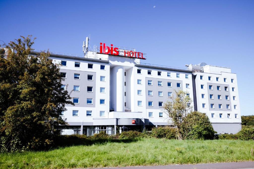 a white hotel with a sign on top of it at Ibis Luxembourg Airport in Luxembourg