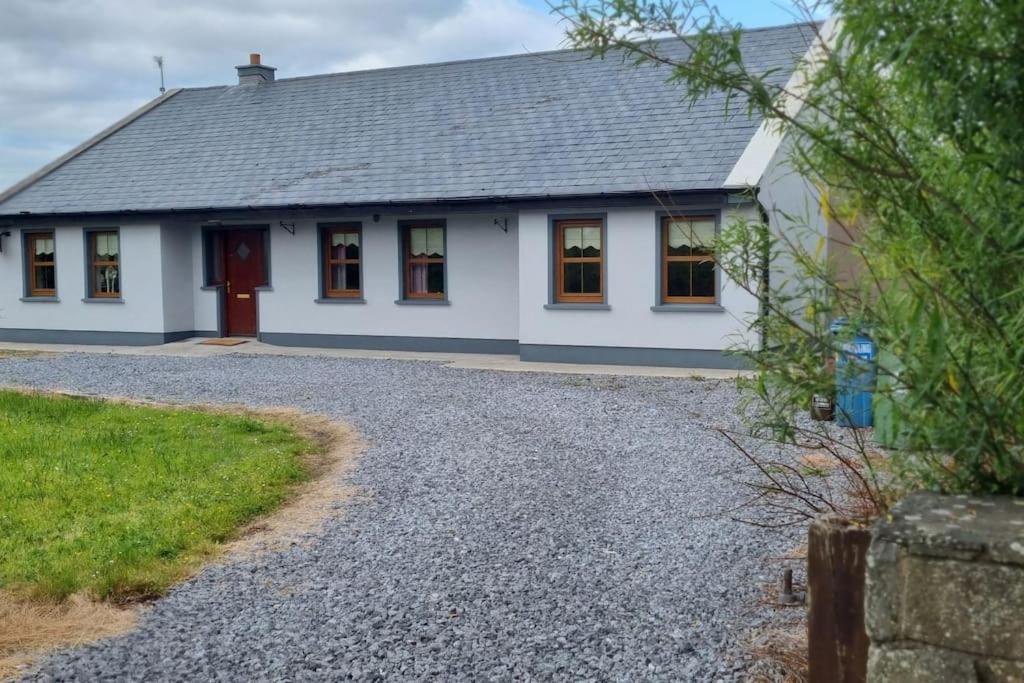 a white house with a red door and a gravel driveway at ocean fields view in Ahnagh Cross