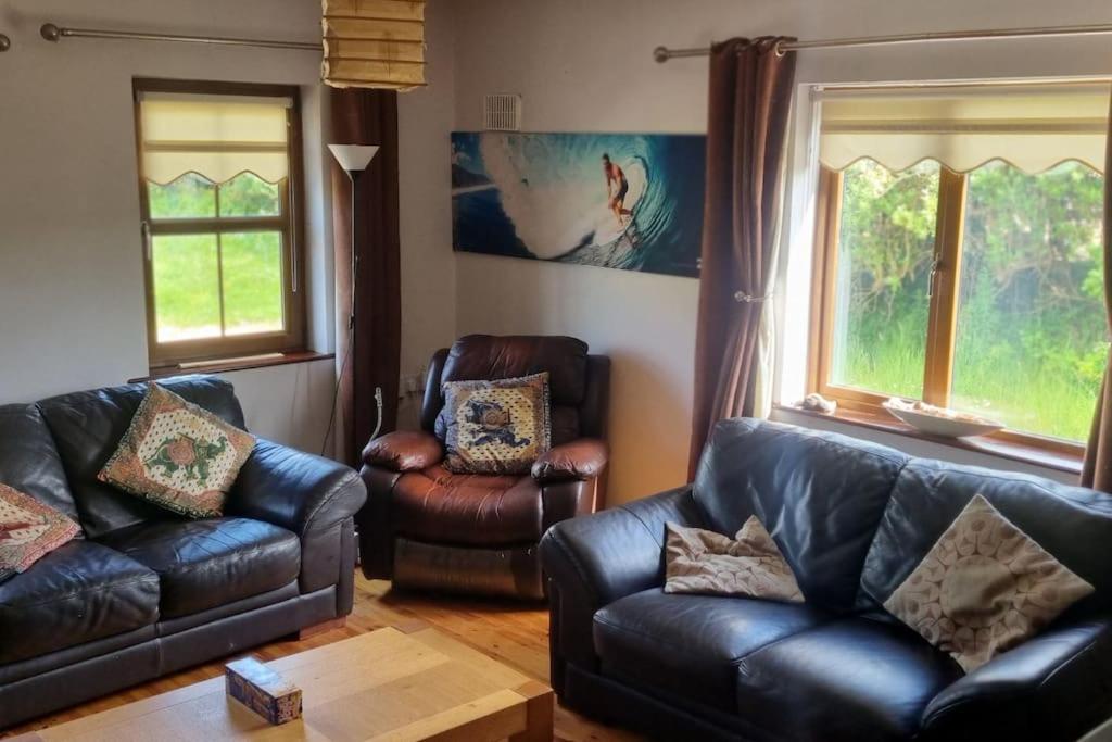 a living room with two leather couches and a table at ocean fields view in Ahnagh Cross