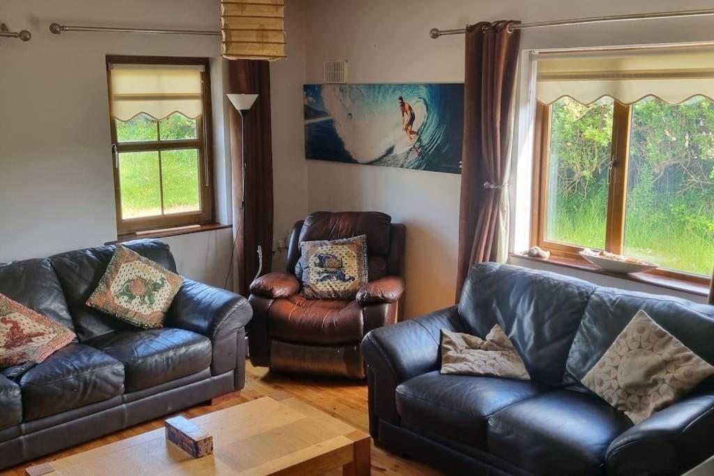 a living room with two leather couches and a table at ocean fields view in Ahnagh Cross