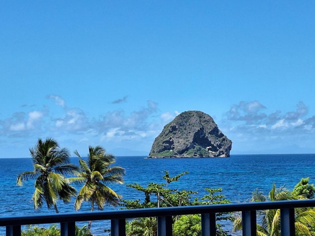 a view of a rock in the ocean with palm trees at Studio A101, près de la mer Village du Diamant in Le Diamant