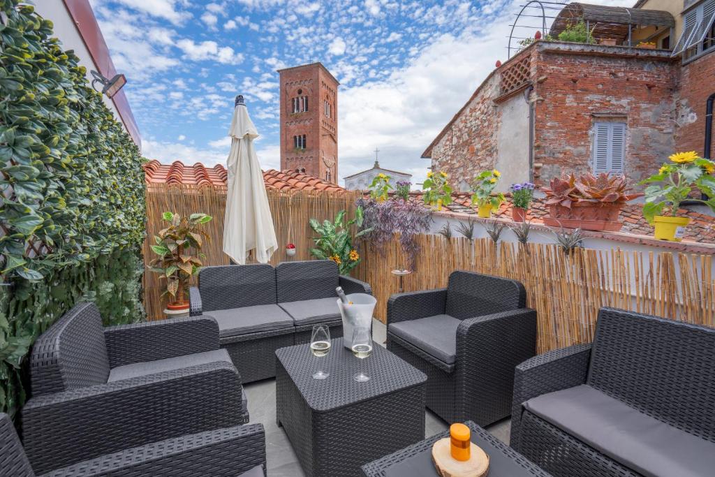 een terras met zwarte stoelen, een tafel en een parasol bij Lucca Old Town Apartment in Lucca