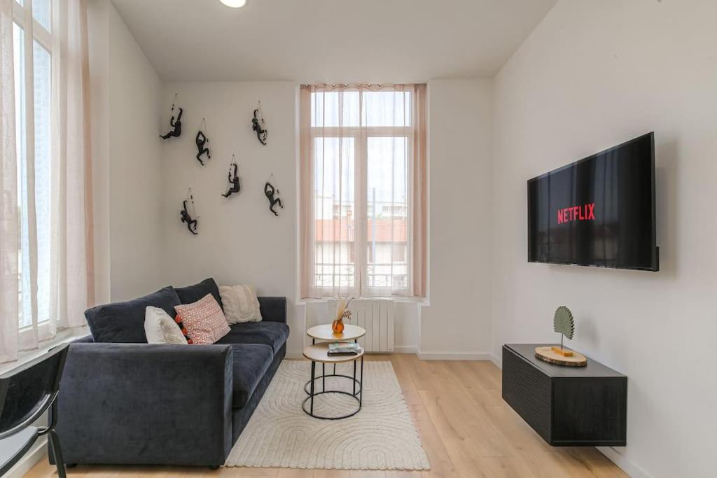 Una sala de estar con un sofá y un televisor en una pared. en Selva, appartement cozy, Lyon 8ème, en Lyon