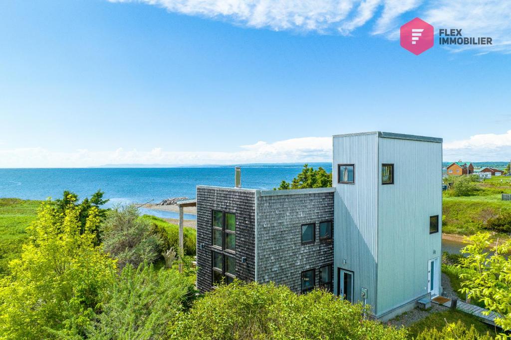 un'immagine di una casa con l'oceano sullo sfondo di La Maison de l'Échouerie on Chaleur Bay Seaside a Bonaventure