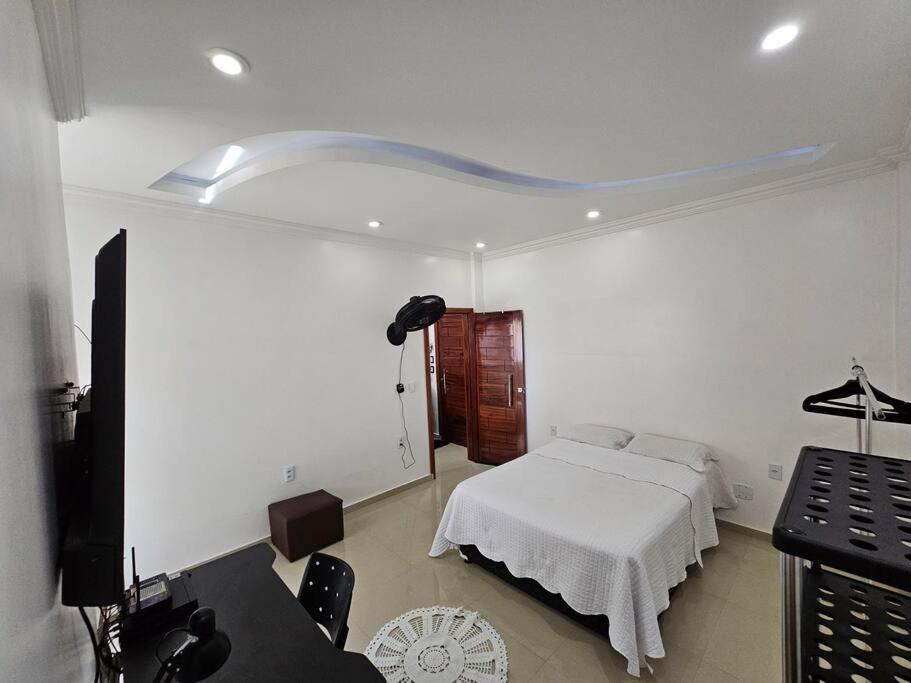 a white bedroom with a bed and a desk at Apartamento Premium in Parintins