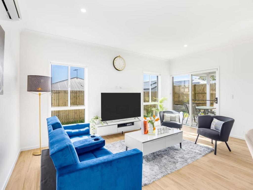 ein Wohnzimmer mit blauen Stühlen und einem Fernseher in der Unterkunft Brand New Comfy Home 4Bedroom designer furniture in Springfield Lakes