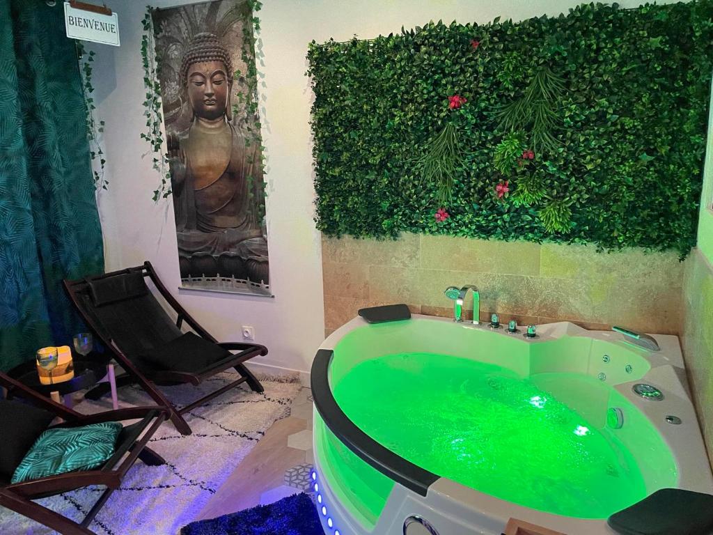 un bagno con una vasca verde e una statua di Maison Prestige Le Donjon des Plaisirs Jacuzzi a Montluel