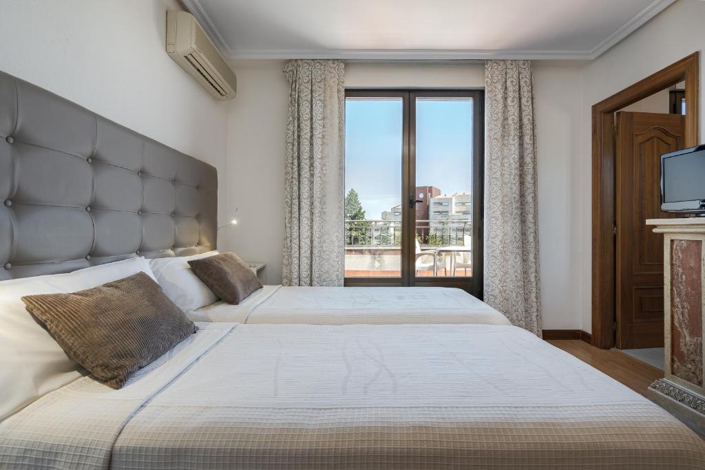 a bedroom with two beds and a large window at Hotel Eurowest in Salamanca