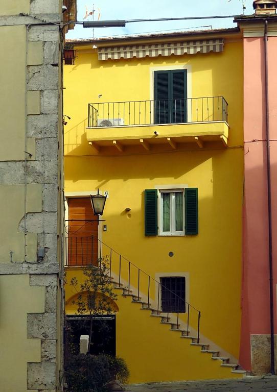 a yellow building with stairs and a balcony at Marivò Apartment in Rapolano Terme