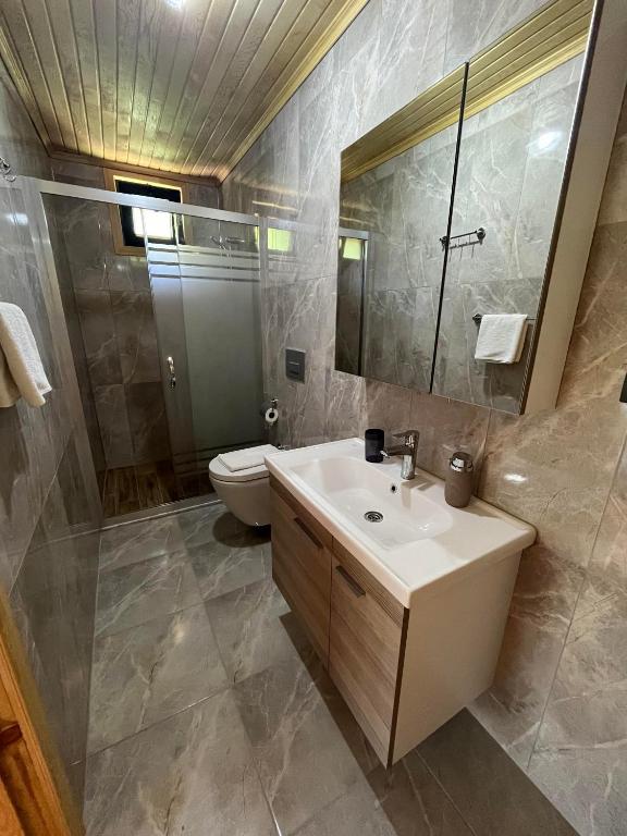 a bathroom with a sink and a toilet and a mirror at Olympos Yavuz Hotel in Cıralı