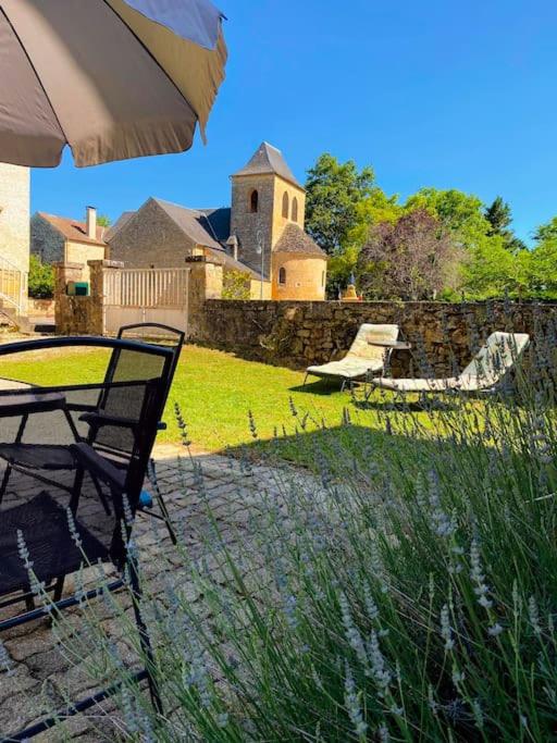- une table et une chaise avec un parasol dans la cour dans l'établissement Charming house in quiet village, à Saint-Cirq-Madelon
