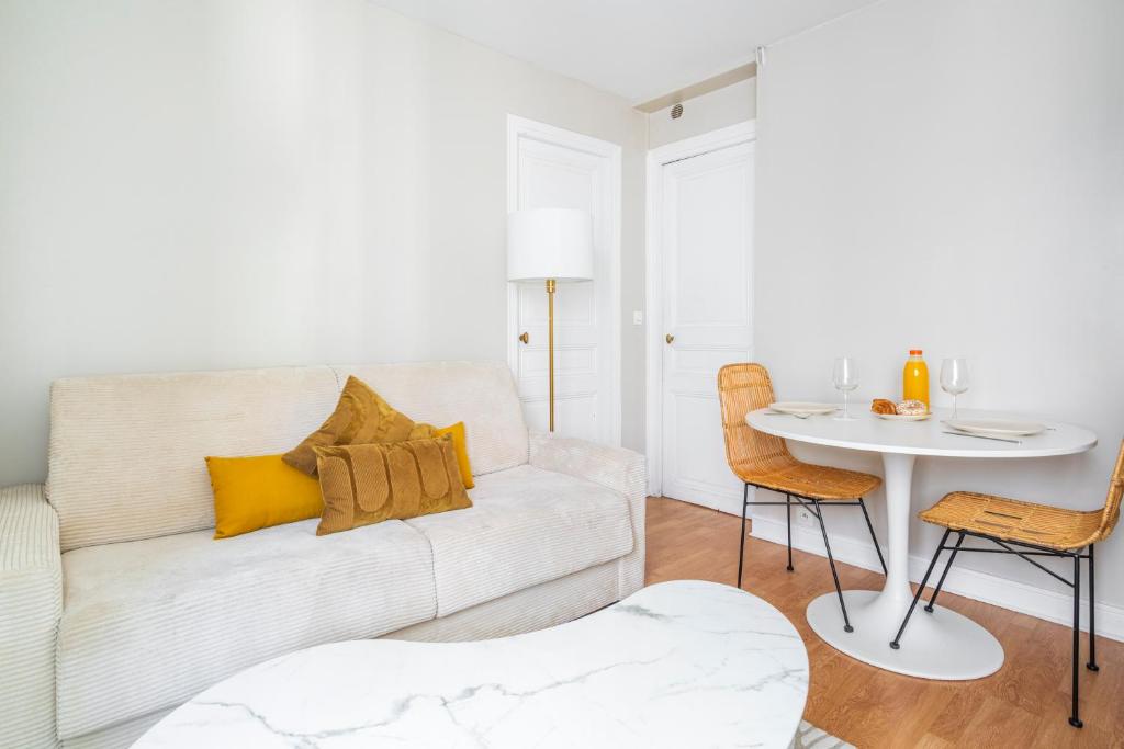 un salon avec un canapé blanc et une table dans l'établissement Appartement au cœur de Paris Montparnasse, à Paris