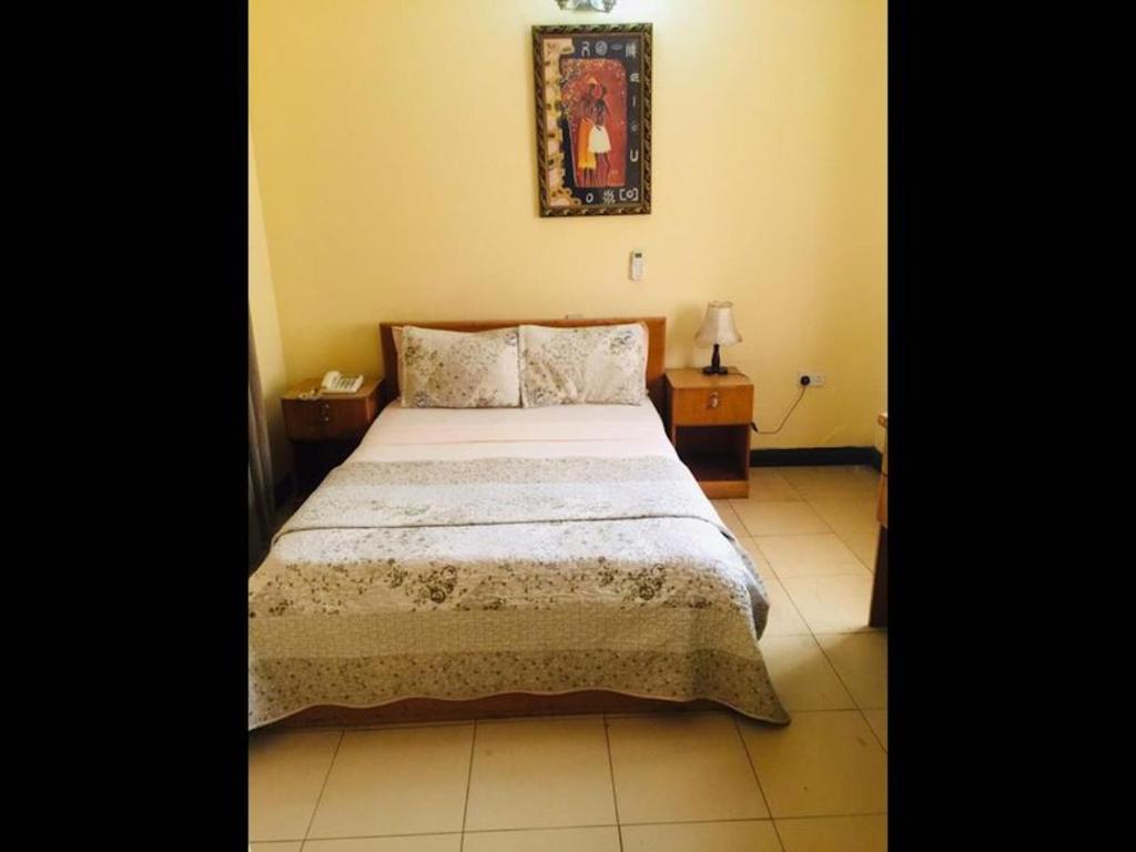 a bedroom with a bed and a picture on the wall at Single Room - 1st Floor in Accra