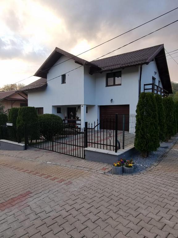 a white house with a black fence at Pensiunea Azurul in Sovata