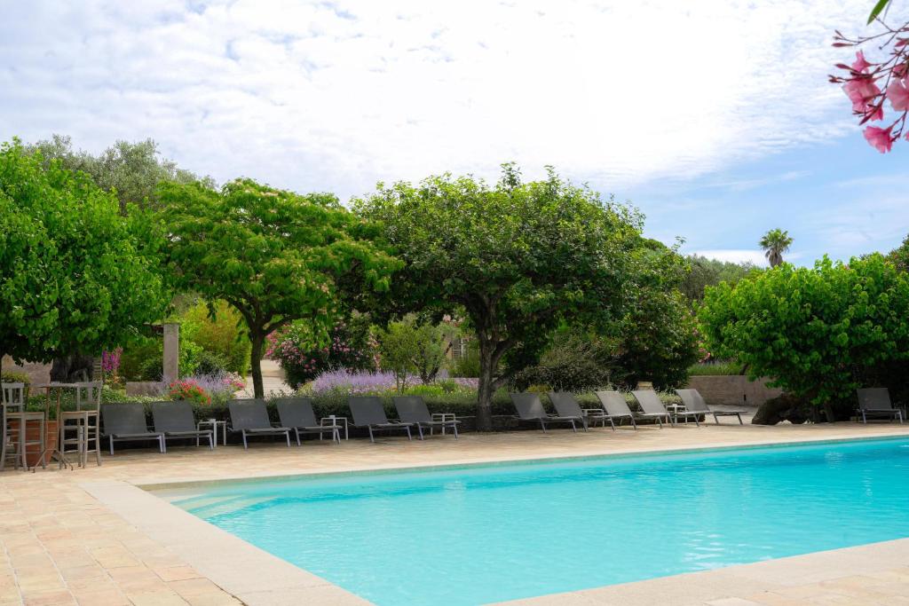 a swimming pool with chairs and trees in a yard at Hôtel La Figuière in Saint-Tropez