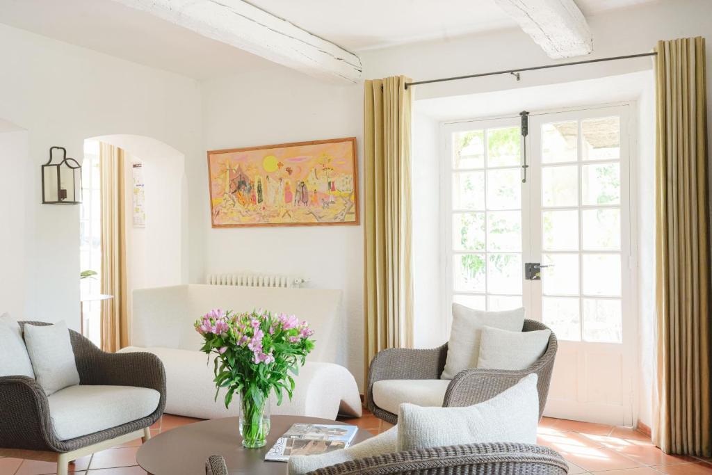 a living room with chairs and a table with a vase of flowers at Hôtel La Figuière in Saint-Tropez