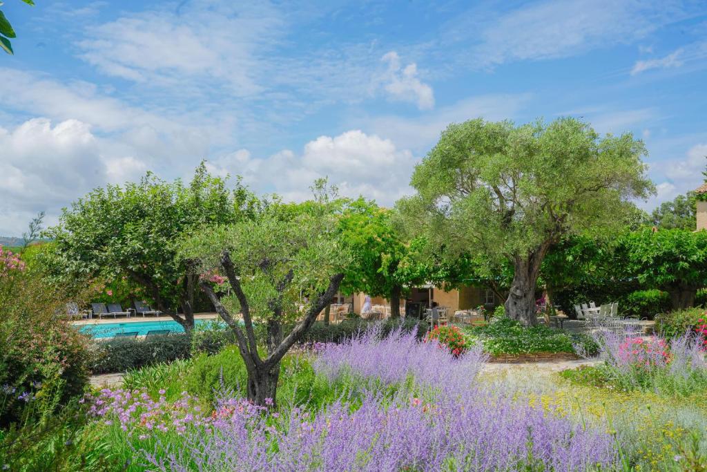 a garden with purple flowers and trees and a pool at Hôtel La Figuière in Saint-Tropez