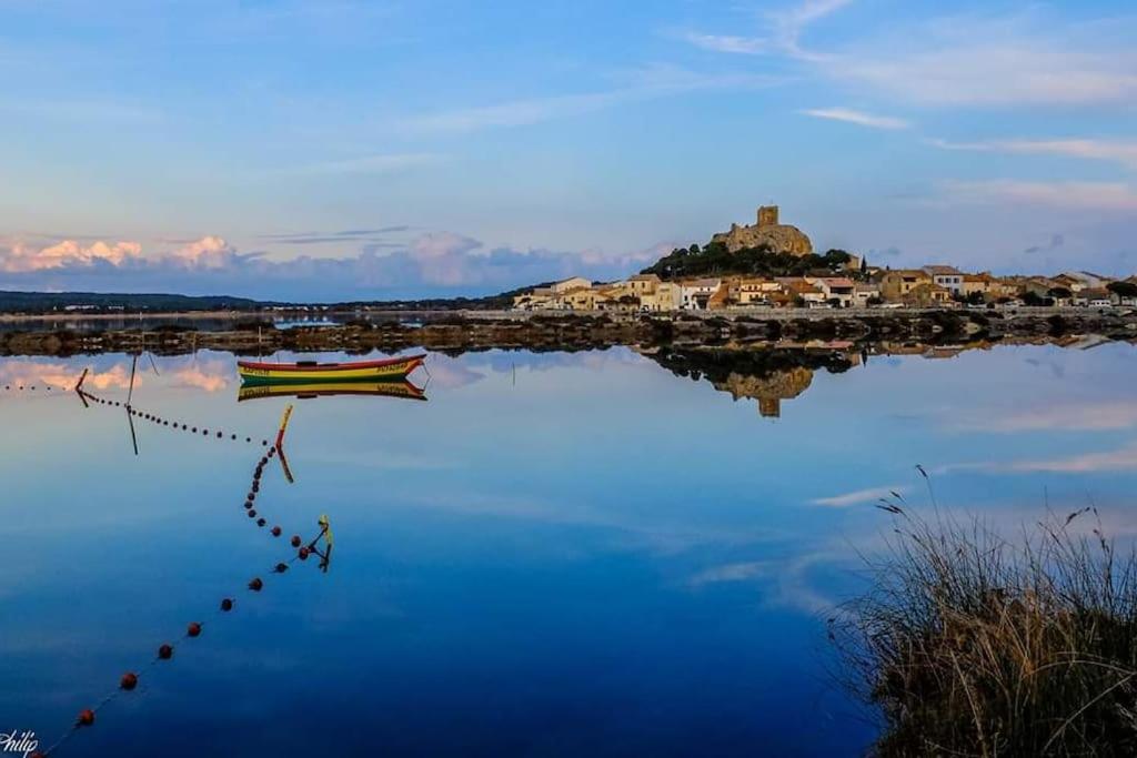 un bateau sur l'eau avec une petite île au loin dans l'établissement Gruissan plage des chalets petit logement en rdc, à Gruissan