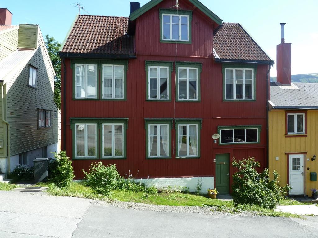 a red house with white windows on a street at Red Old House Tromsø Apartment in Tromsø