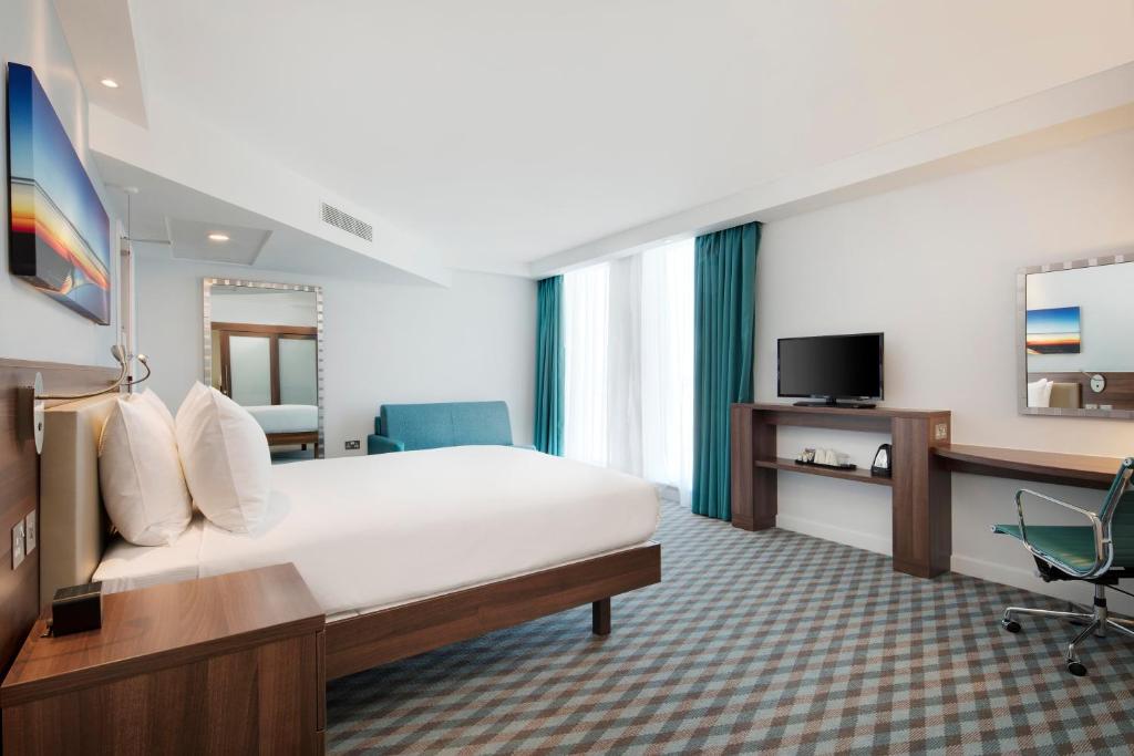 a hotel room with a large bed and a television at Hampton By Hilton London Stansted Airport in Stansted Mountfitchet