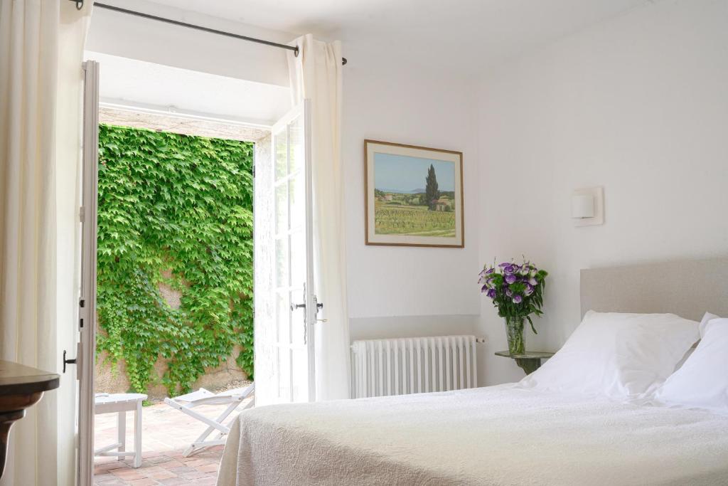 a white bedroom with a bed and a window at Hôtel La Figuière in Saint-Tropez
