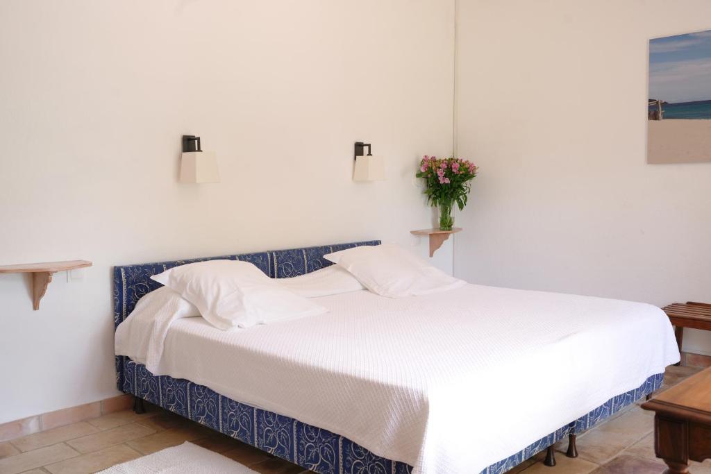 a white bed in a bedroom with a vase of flowers at Hôtel La Figuière in Saint-Tropez