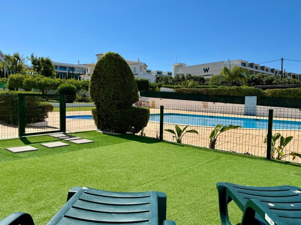 Dos sillas y una valla con cancha de tenis. en Galé Premium House - Pet Friendly, en Albufeira
