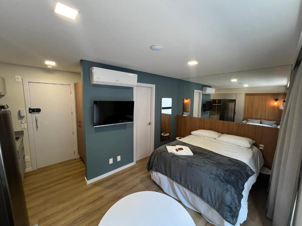 a hotel room with a bed and a flat screen tv at Loft de Luxo "Novo" no Coração de Blumenau a 10min a Pé da Vila Germânica in Blumenau