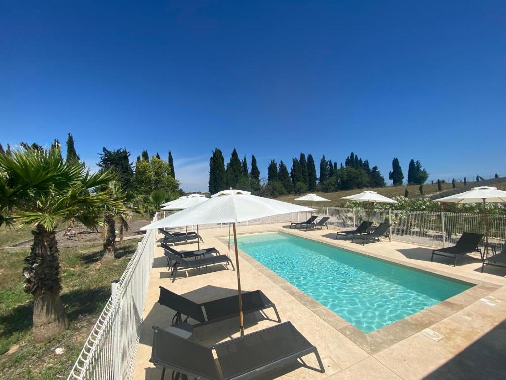 a swimming pool with chairs and umbrellas next to a pool at Gite pour 8 p avec Piscine sur domaine 3Ha in Béziers