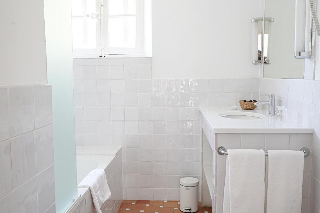 a white bathroom with a sink and a tub at Hôtel La Figuière in Saint-Tropez
