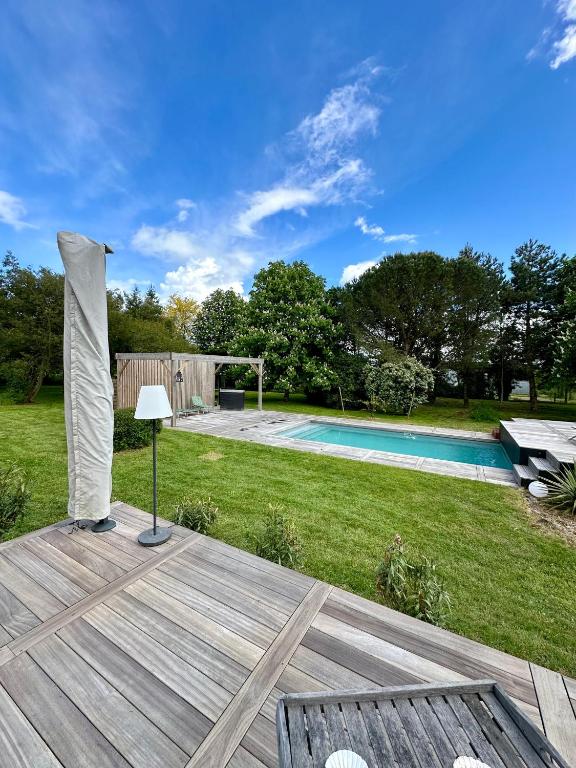une arrière-cour avec une terrasse en bois et une piscine dans l'établissement La salmoniere, à La Roche-Blanche