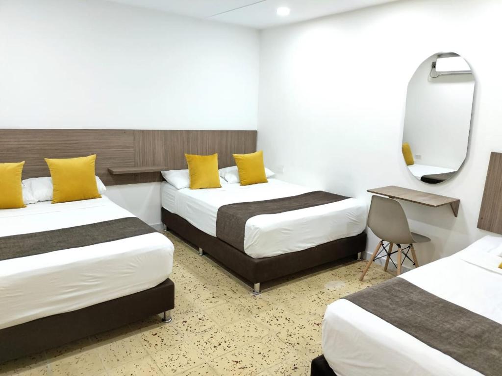 una camera d'albergo con due letti e uno specchio di Ayenda Hotel Helenas a Ríohacha